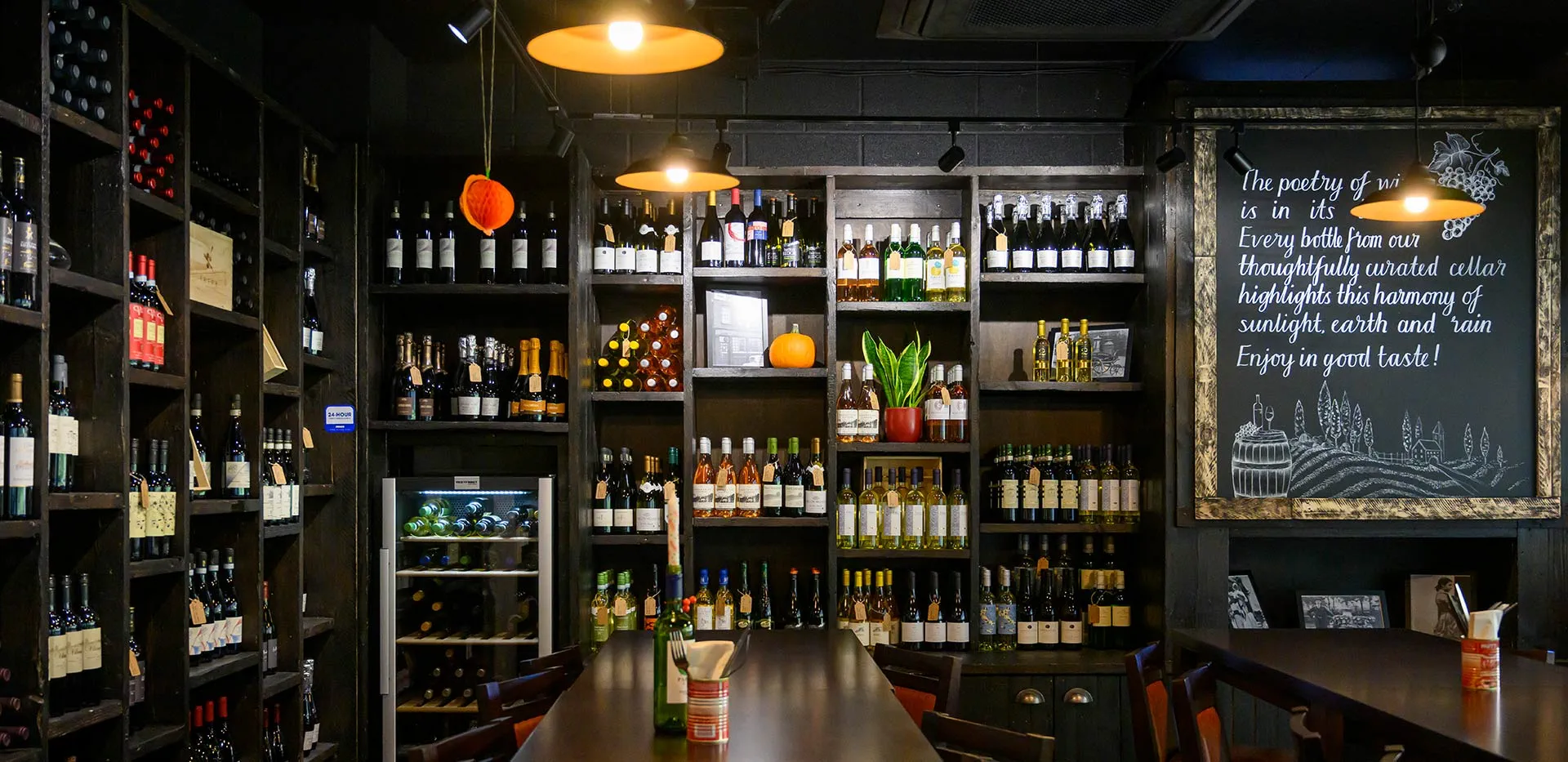Interior view of a wine cellar with numerous bottles on shelves and a large blackboard.