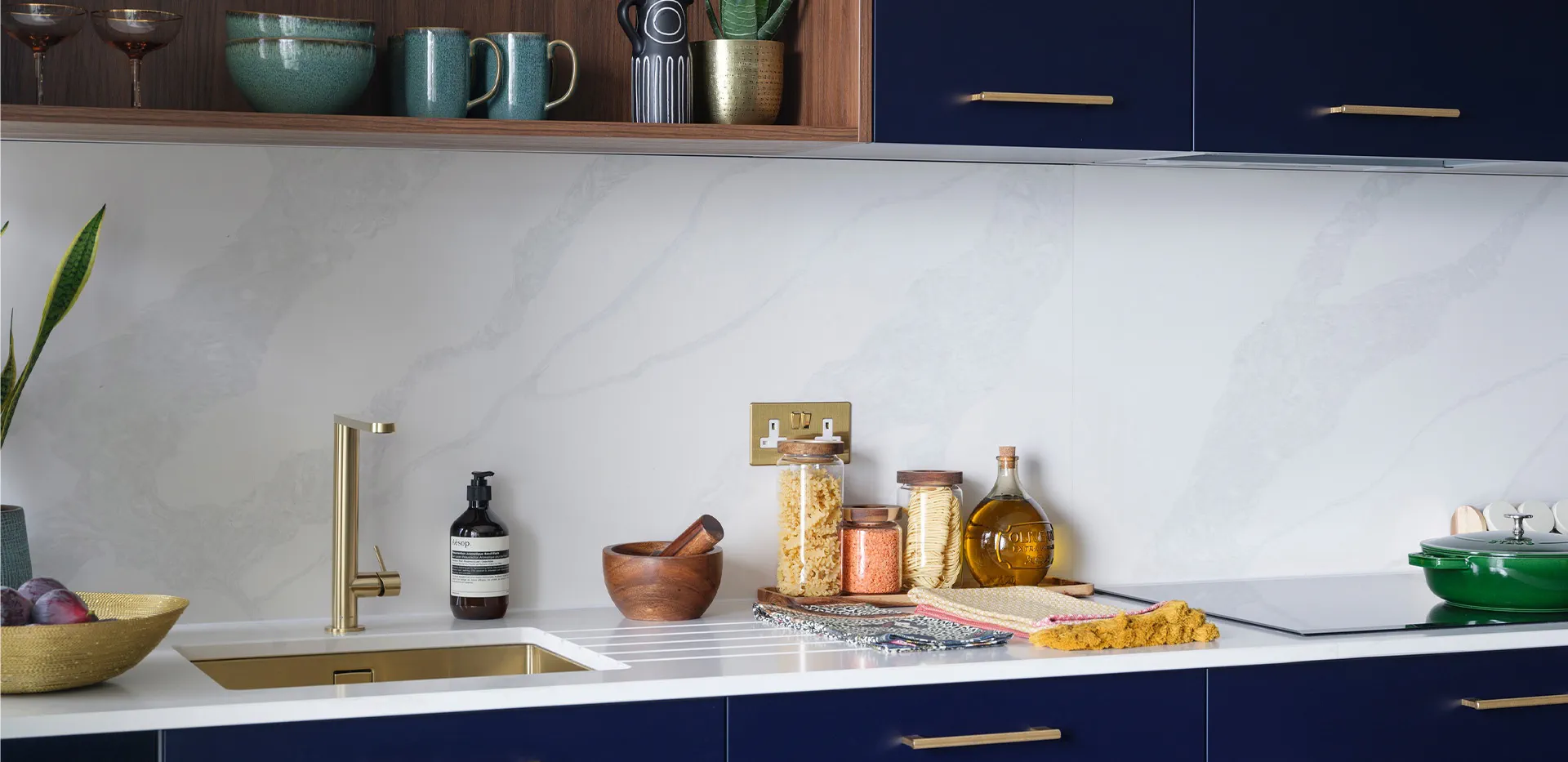 Modern kitchen counter with brass faucet, gold undermount sink, and stylish storage containers.