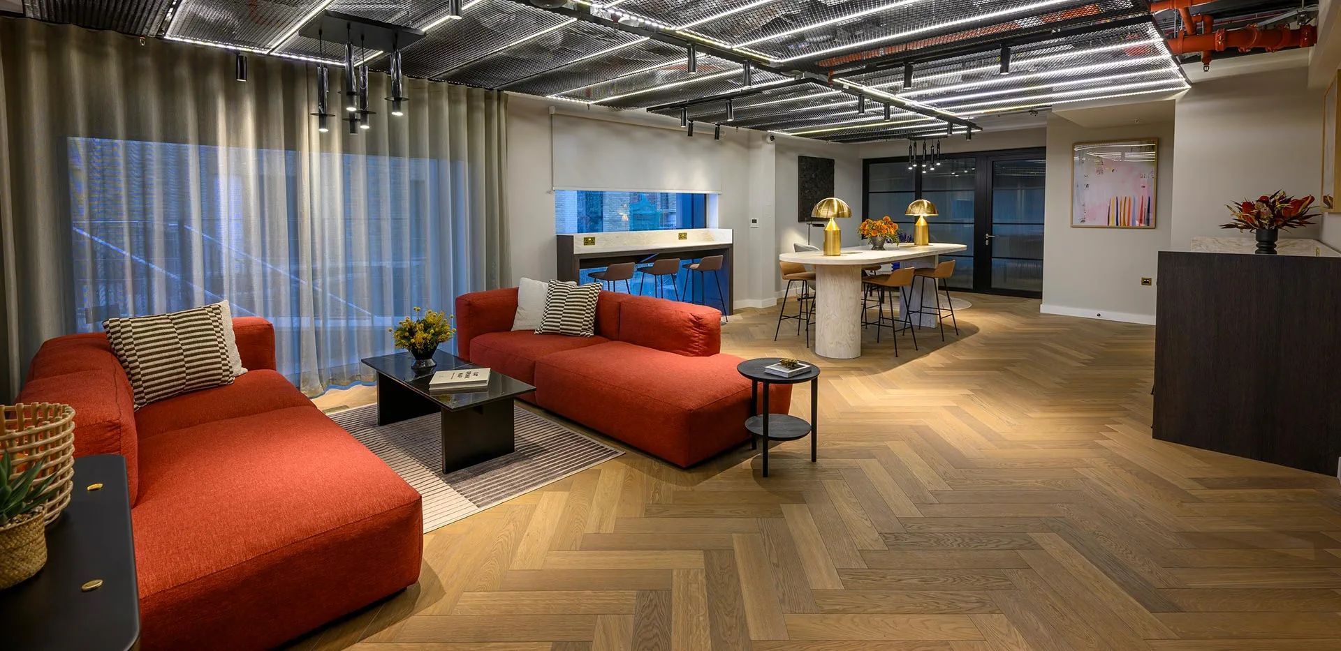Resident amenity lounge with a red sofa, dining table, and co-working space