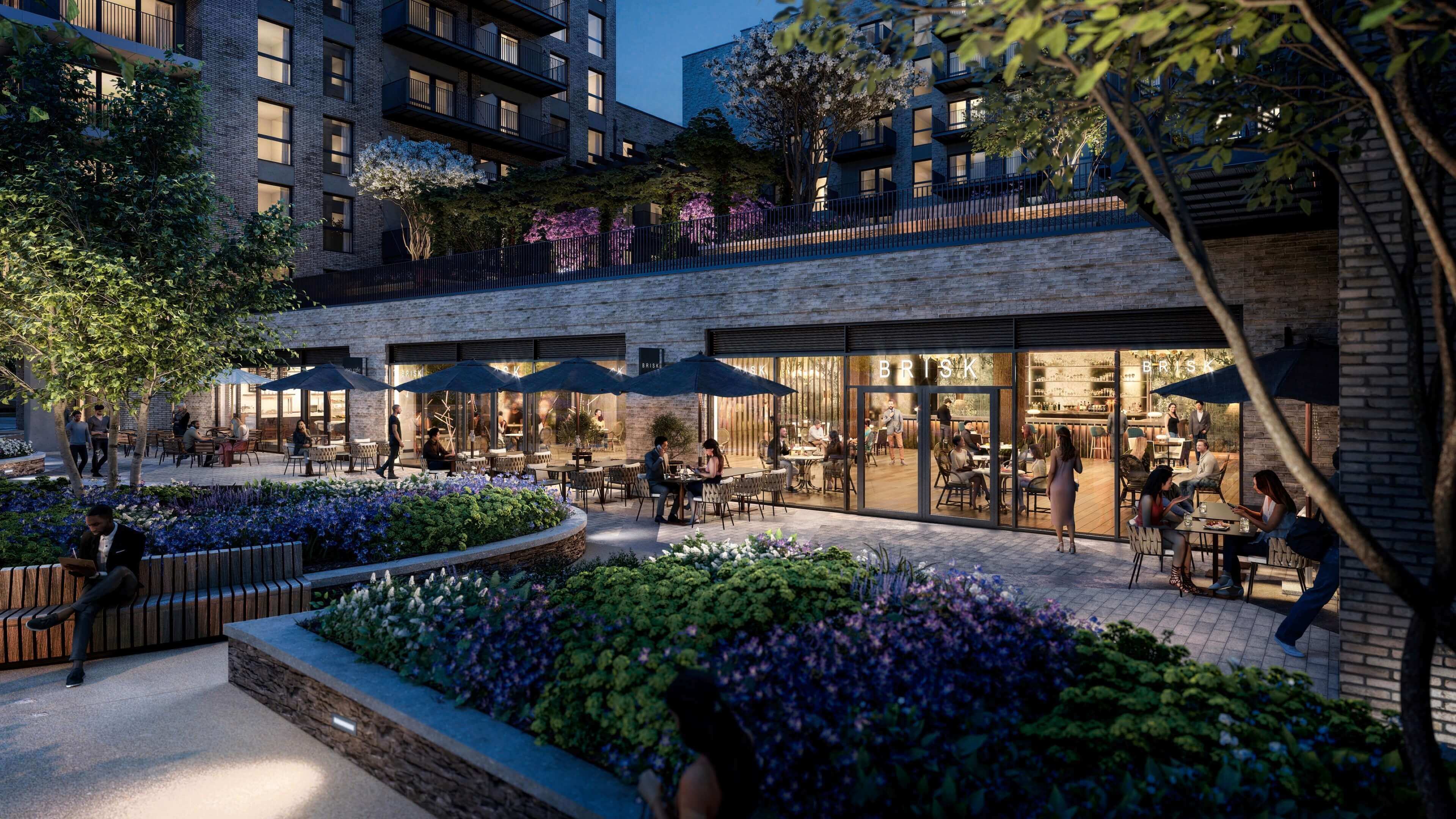 The 'Brisk' restaurant with illuminated outdoor seating under a London residential block at night. Prime commercial property.